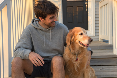 Customer wearing hoodie with dog on porch